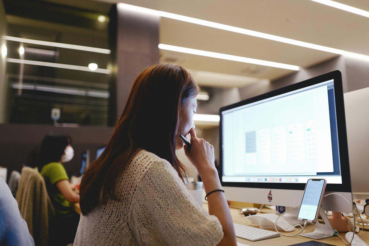 a woman sitting in front of a computer on a desk